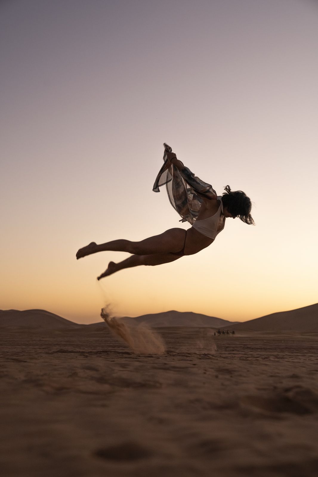 Anita leaping over the desert sand at sunset, a scarf flying behind her